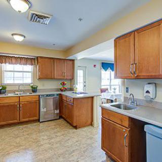 A spacious kitchen with wooden cabinets, modern appliances, and natural light from a window.
