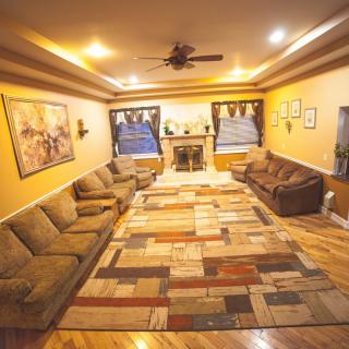 A spacious living room with multiple sofas, a large patterned rug, and a fireplace centerpiece.