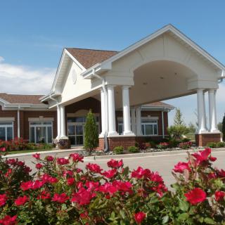 A beautifully landscaped entrance to a building with red flowers in the foreground.