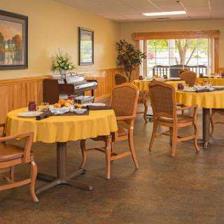 A cozy dining area featuring yellow tablecloths and wooden chairs, creating a warm and inviting atmosphere.