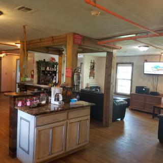A cozy living space with wooden beams and furniture, showcasing a connected kitchen area and a TV.