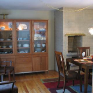 A cozy dining room featuring a wooden table and chairs, a display cabinet, and an inviting fireplace.