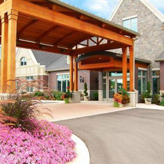 A beautifully landscaped building entrance with a wooden canopy and flowerbeds.