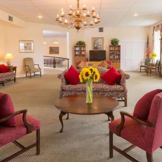 A cozy living room with elegant furniture and a central chandelier.