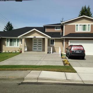 A suburban house with a driveway and a car parked in front.
