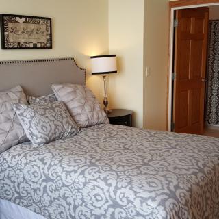 A cozy bedroom featuring a neatly made bed with patterned bedding and a stylish lamp.