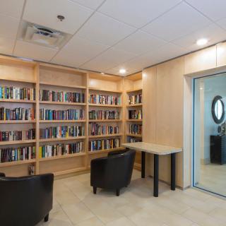 A cozy reading area with bookshelves, seating, and a table.