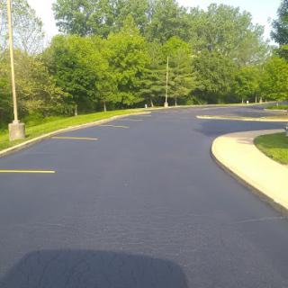 A peaceful curved asphalt road surrounded by lush greenery.