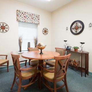 A cozy dining room with a round wooden table and chairs, adorned with wall art and elegant decor.