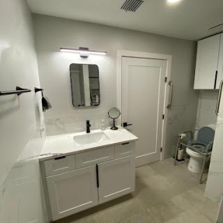 A stylish and modern bathroom featuring a sleek vanity, mirror, and essential fixtures.