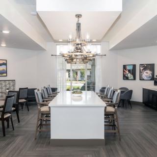 A modern dining room with a central chandelier and ample seating around a long table.