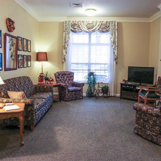 A cozy living room with patterned furniture and a television next to a large window.