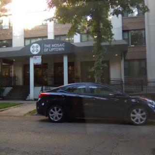 A sleek black car parked in front of a modern building with a sign that reads 'THE MIDDLE STATION'.