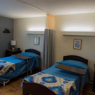 A cozy shared bedroom featuring two beds with blue bedding and decorative wall art.