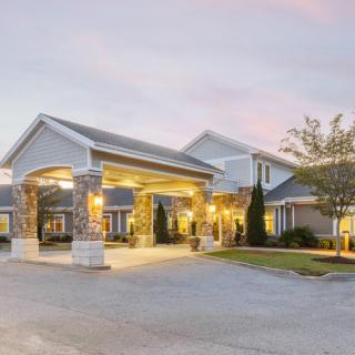 A well-lit building entrance during the evening with a driveway.