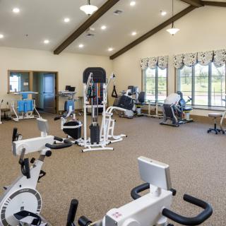 A spacious gym with various exercise equipment and bright natural lighting.