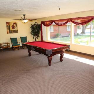 A spacious game room featuring a red pool table with natural light streaming through large windows.