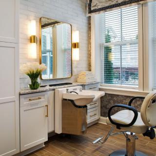 A stylish hair salon interior with a mirror, sink, and comfortable chair.