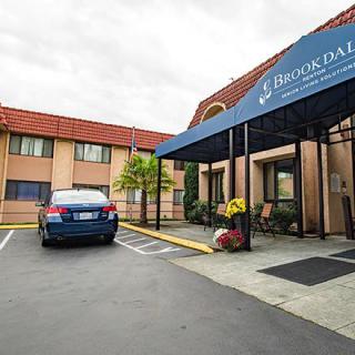 The entrance of a hotel with a car parked outside under an awning.