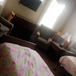 A cozy room with beds, chairs, and a television.