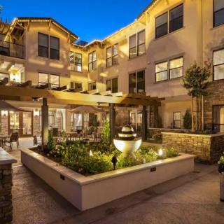 A beautifully lit residential courtyard at night, featuring elegant architecture and lush landscaping.