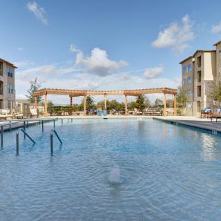 A serene outdoor swimming pool surrounded by apartment buildings and clear blue skies.