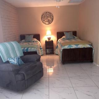 A cozy bedroom with two twin beds, an armchair, and warm lighting.
