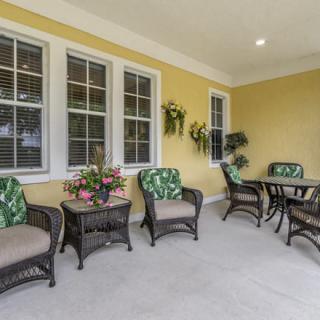 A cozy patio area with wicker furniture and potted plants against a yellow wall.