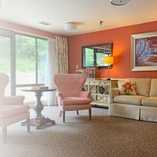 A cozy living room with comfortable armchairs, a sofa, and a decorative coffee table set against an orange accent wall.