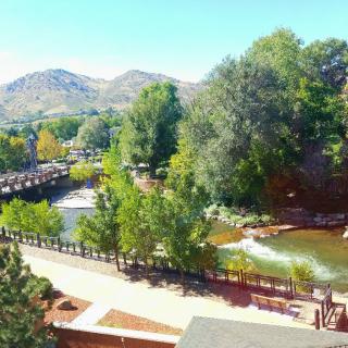 A scenic view of a river with a bridge, surrounded by lush trees and mountains in the background.
