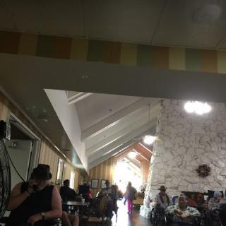 A spacious interior of a lounge area with people seated and engaging in activities.