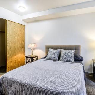 A cozy bedroom with a neatly made bed, nightstands, and a closet.