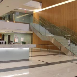 A modern lobby with a sleek staircase and reception desk.