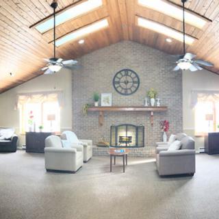 Spacious living room with a vaulted ceiling and skylights, featuring a central fireplace and modern furniture.
