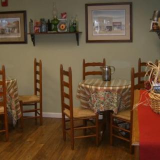 A cozy restaurant interior featuring wooden tables and chairs, with decorative paintings on the walls.
