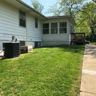 A backyard view of a house with a well-maintained lawn and a small patio area.