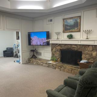 A cozy living room featuring a stone fireplace, wall-mounted television, and comfortable recliner.