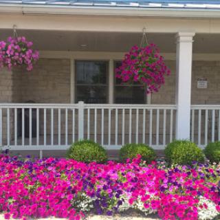 A beautifully landscaped front porch adorned with vibrant hanging baskets and colorful flowers.