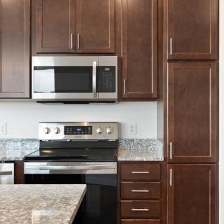Modern kitchen with stainless steel appliances and dark wood cabinets.