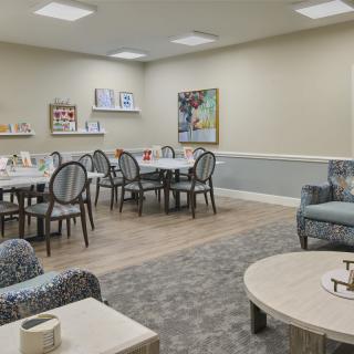 A well-appointed dining area with neatly arranged tables and chairs, complemented by artwork on the wall.
