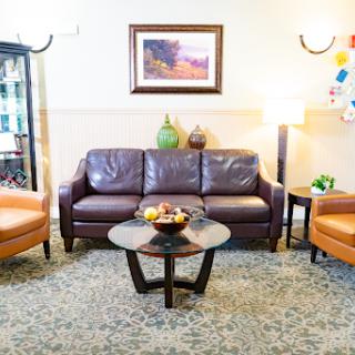 A cozy living room setup featuring a brown sofa, two orange chairs, and a circular coffee table adorned with fruit.