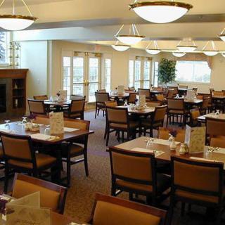 An empty dining hall with neatly arranged tables and chairs, featuring warm lighting.