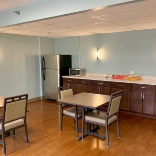 A modern kitchen and dining area with tables, chairs, a refrigerator, and a microwave.