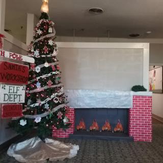 A beautifully decorated Christmas tree next to a cozy fireplace.