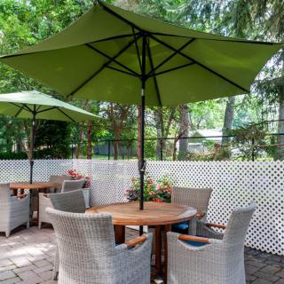 A cozy outdoor patio setting with wicker chairs and a wooden table under a green umbrella.
