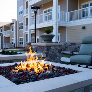 A modern apartment complex with a stylish outdoor fire pit and seating area.
