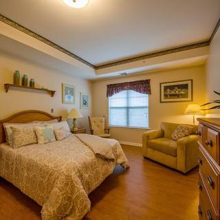 A cozy, well-decorated bedroom featuring a comfortable bed, nightstands with lamps, and a plush armchair by the window.