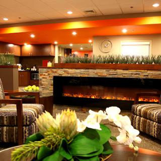 A cozy and modern lobby area featuring elegant furniture, a decorative fireplace, and vibrant colors.