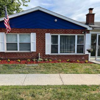 A charming brick house with a blue exterior and an American flag proudly displayed.