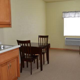 A simple and cozy kitchen and dining area featuring a table and chairs, with light-colored walls for a bright atmosphere.